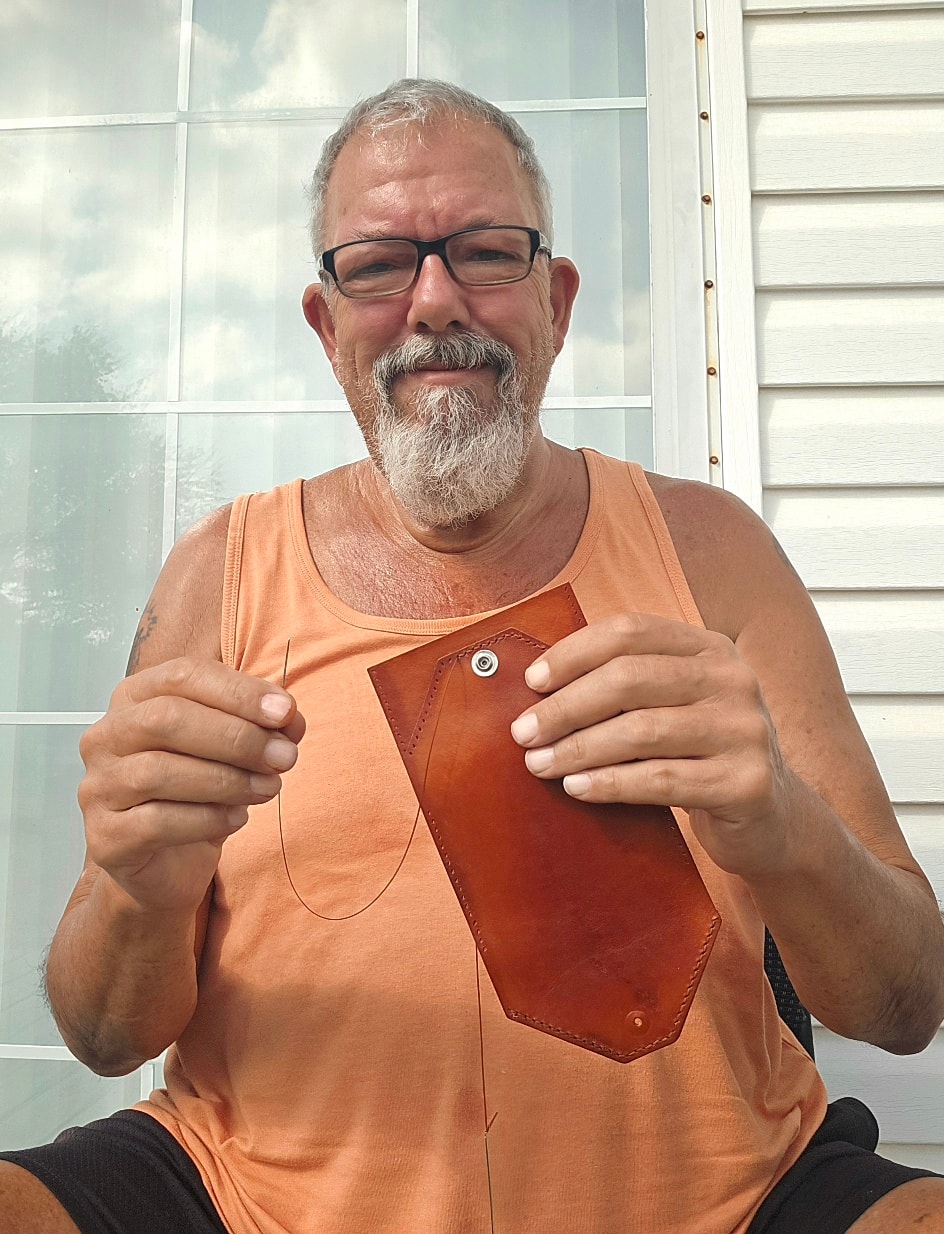 Paul, maker at Big Dog Leather, holding a handmade leather wallet