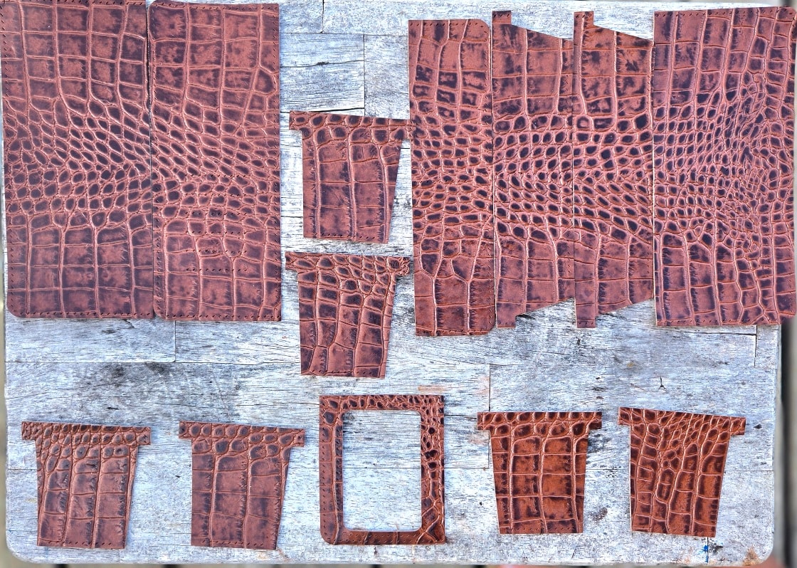 Cut leather pieces laid out on wood before assembly