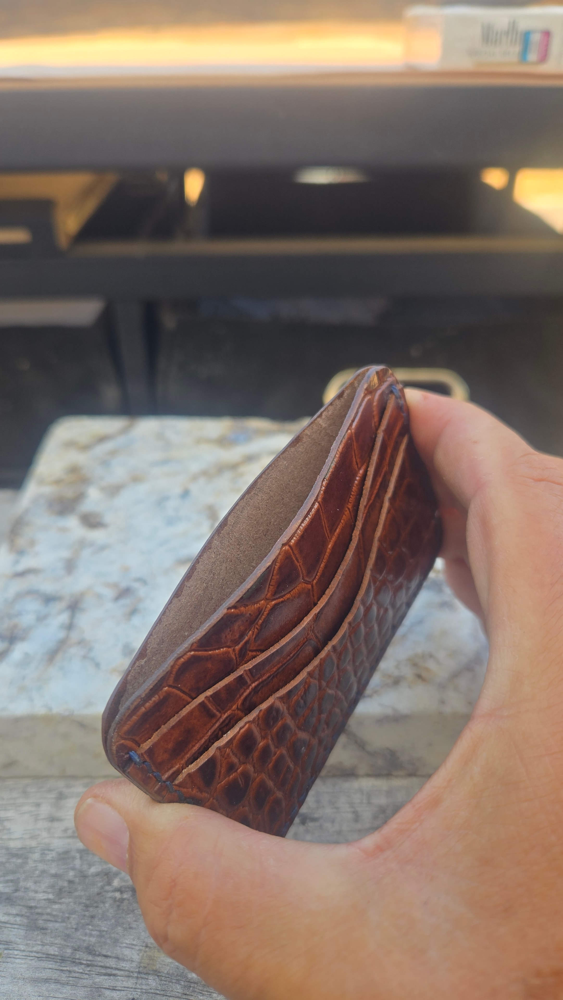 M3 Mauri croc embossed wallet in hand — edge profile showing slim build