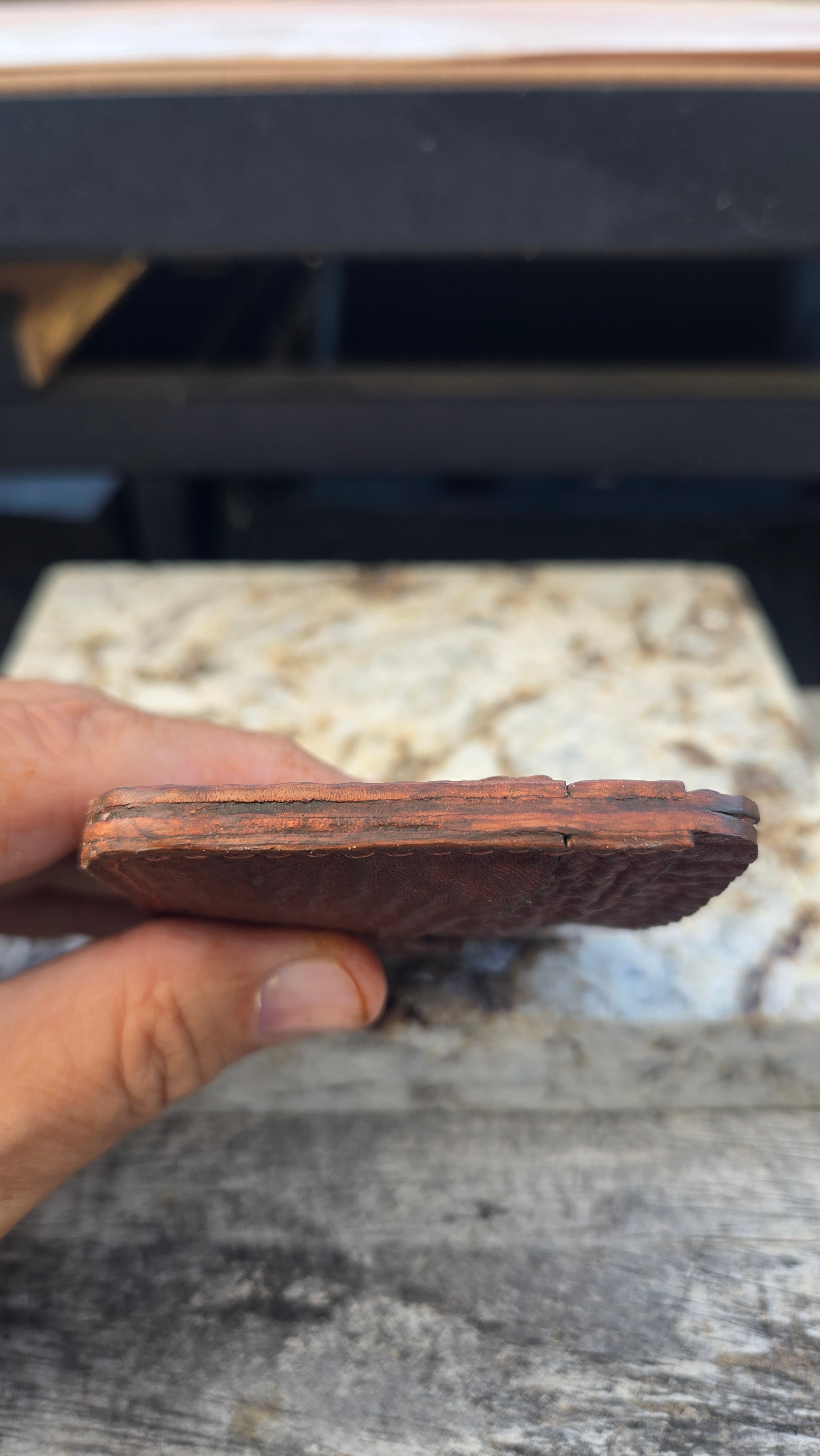Wallet in hand — top edge showing stitching detail