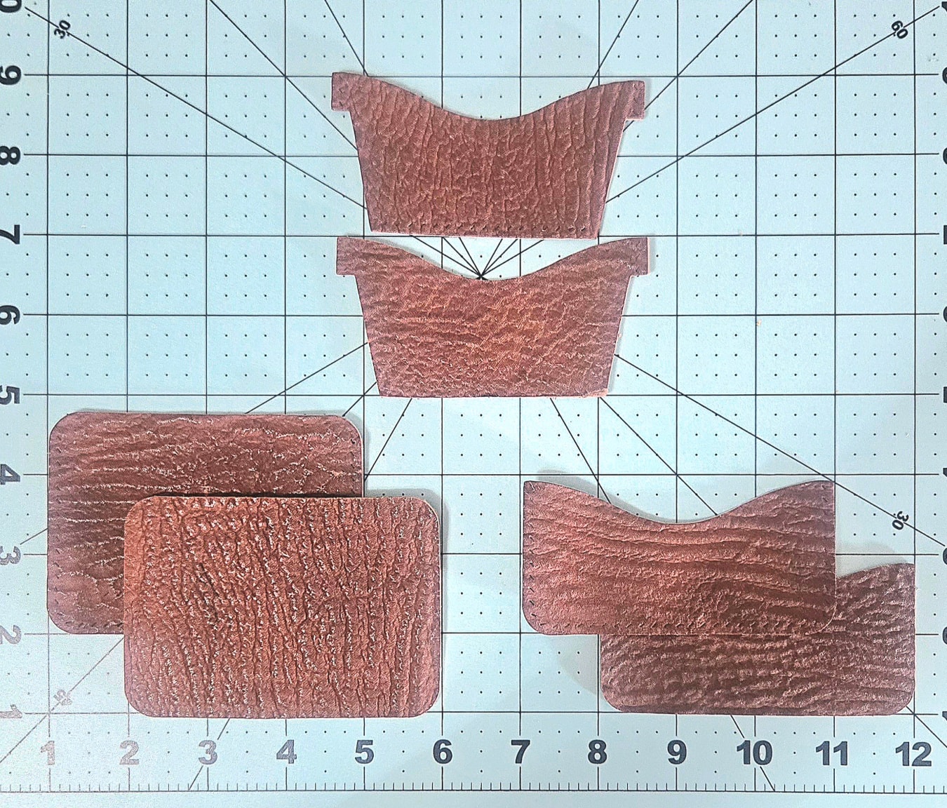 Cut leather pieces laid out on cutting mat before assembly